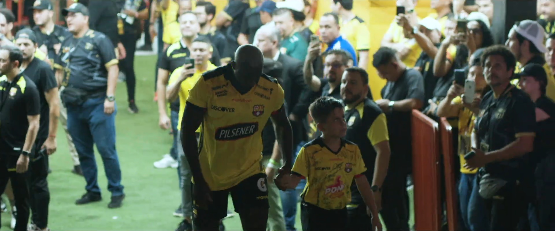 Fotograma del showreel 2026 de Spectro: un jugador saliendo al campo con un niño de la mano